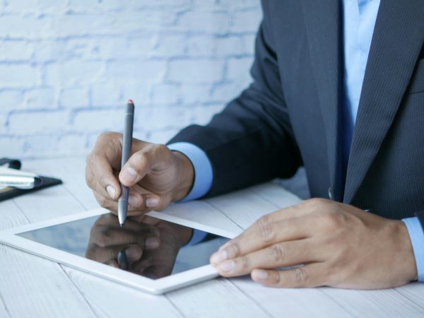 Man in suit using stylus on tablet for business work indoors
